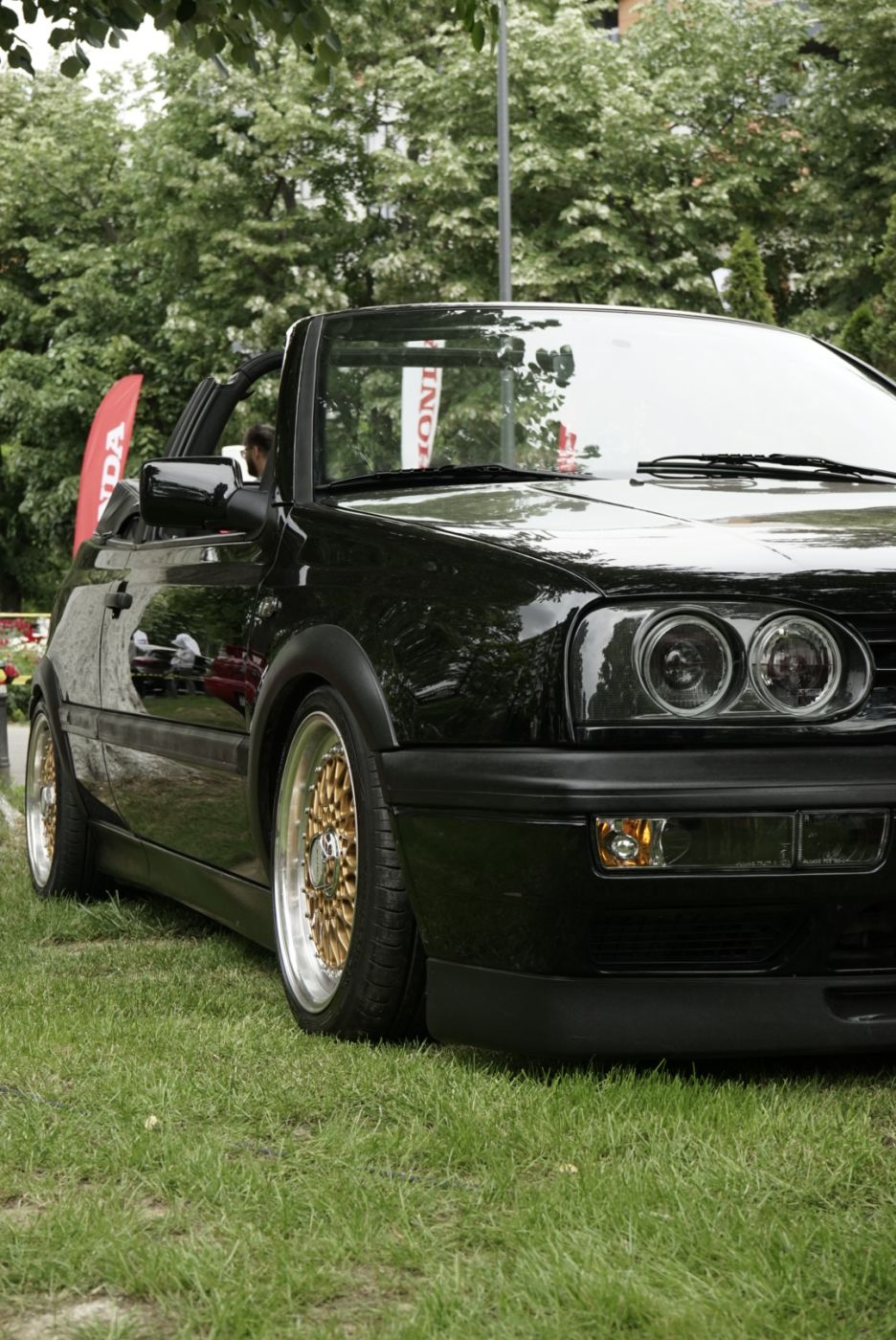 Volkswagen Golf Cabrio negru cu jante BBS aurii la întâlnire auto