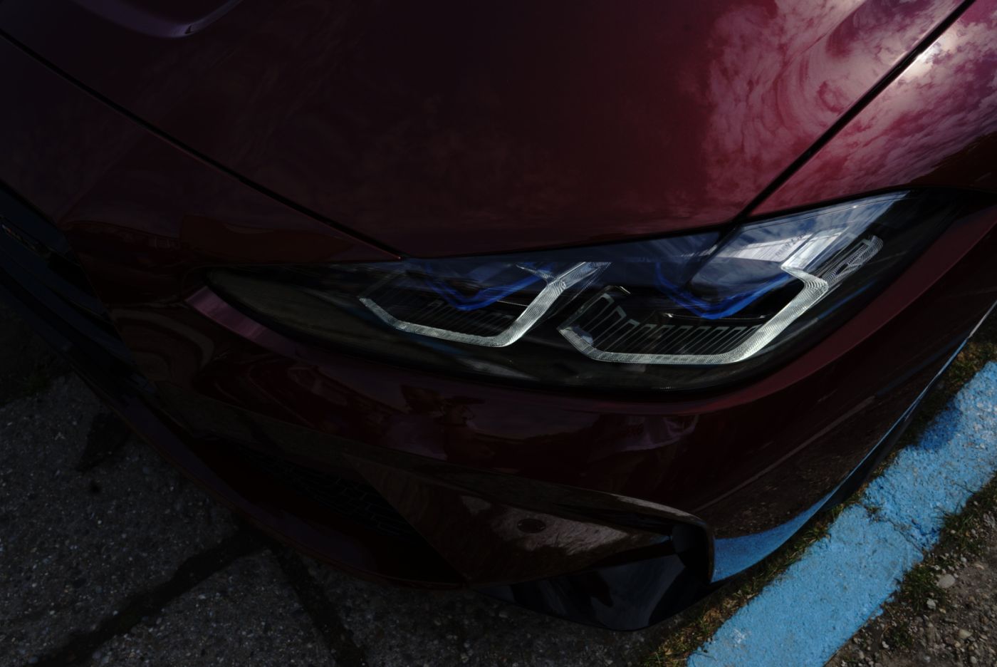 Detaliu far și capotă vișinie la o întâlnire auto